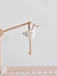 a toy duck hanging from a clothes line on a wooden pole next to a crib