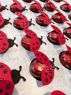 ladybug shaped candy boxes are arranged on a table with red foil coverings