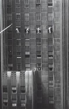 an old black and white photo of people in windows on the side of a tall building