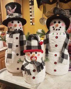 three snowmen in hats and scarfs on a counter