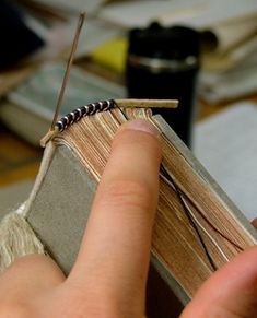 a person holding an open book in their left hand and threading it to another book