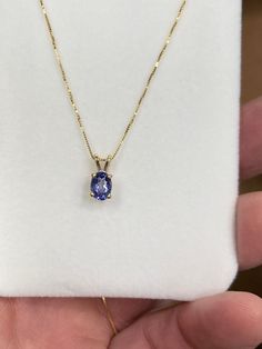 The item is a 14k yellow gold tanzanite pendant and chain. The pendant has four prongs holding in the 7 x 5 millimeter oval tanzanite. The tanzanite weighs 0.85 carats. The box chain is also made of 14k yellow gold. The chain measures 18 inches in length and has a lobster claw catch on the end. We will provide a pendant box. Tanzanite Pendant, Tanzanite Necklace, Silver Flats, Crystal Figurines, Round Stud Earrings, Box Chain, Silver Charms, Lobster Claw, Gold Pendant