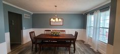 a dining room table and chairs in front of two windows