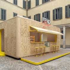 a small food stand in the middle of a courtyard with tables and stools around it