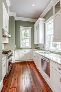 an empty kitchen with white cabinets and wood flooring on the wooden floor is shown