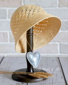 a straw hat with a heart hanging from it's brim on a stand