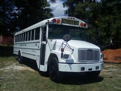 a white school bus parked in the grass