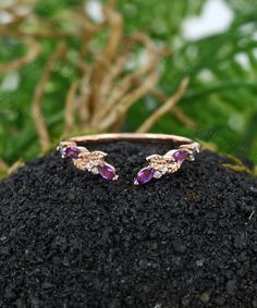 two gold rings with amethysts and diamonds sitting on top of a rock