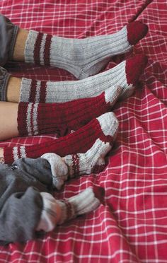 two people wearing red and white socks laying on a bed