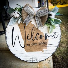 a wooden sign with the state of wisconsin painted on it that says welcome to our home