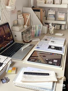 a laptop computer sitting on top of a desk next to other office supplies and papers