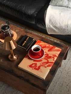 a coffee table with a book and a lamp on it in a living room next to a couch