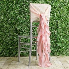 a chair with a pink sash tied to it sitting in front of a green wall