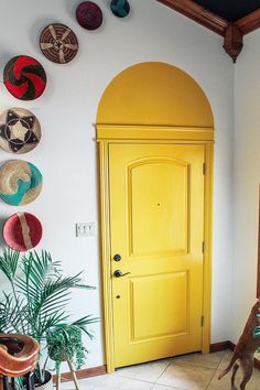 a yellow door in the corner of a room with potted plants on the floor