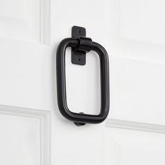 a black door handle on the side of a white door with an open square frame