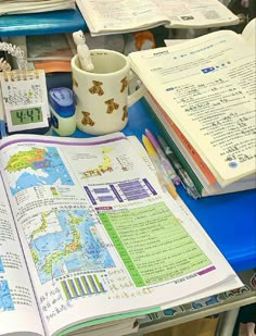 an open book sitting on top of a blue table next to a cup and pen