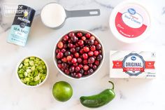 ingredients to make cranberry sauce laid out on a marble counter top with green peppers, avocado, and yogurt