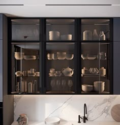 a kitchen with marble counter tops and black cupboards filled with plates, bowls and cups