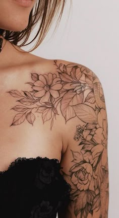 a woman wearing a black dress with flowers on her chest and arm tattooing it's upper half