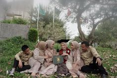 a group of people sitting on top of a grass covered field next to each other