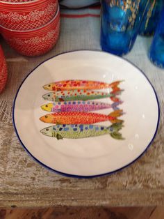 a plate with fish painted on it sitting on a table next to vases and jars