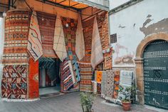 an old building with lots of colorful rugs hanging from it's side wall