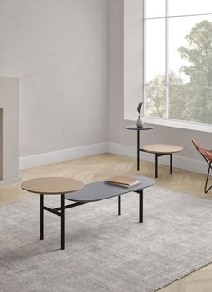 a living room with two tables and a chair in front of a fire place on the wall