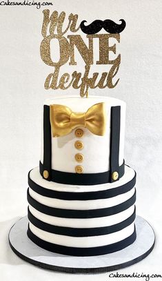 a white and black striped cake with a gold bow tie on top that says we are onederful