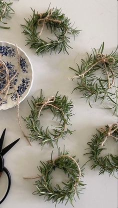 scissors are on the table next to some rosemary wreaths and twine with rope