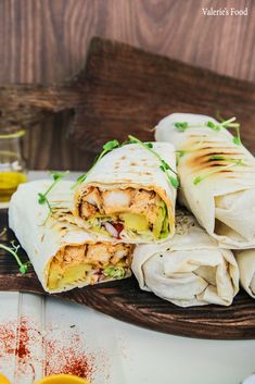 two burritos cut in half sitting on a cutting board next to orange slices