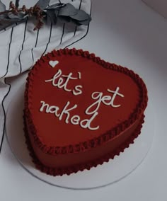 a red heart shaped cake with let's get naked written on it