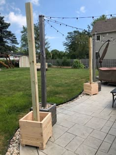 an outdoor patio with wooden planters and string lights strung over the back yard area