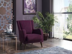 a purple chair sitting in front of a window next to a table with a potted plant