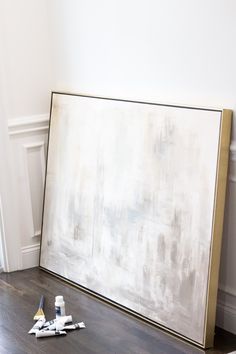 a large white painting sitting on top of a wooden floor next to paint rollers