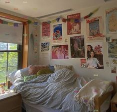 an unmade bed in a bedroom with posters on the wall