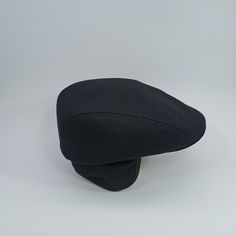 a black hat is sitting on a white surface and it's made out of wool