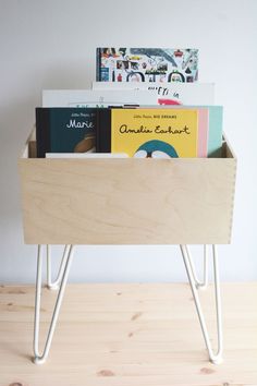 a wooden box with books in it sitting on top of a table next to a wall