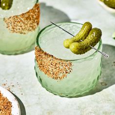 two glasses with pickles in them sitting on a table