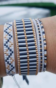 a close up of a person's arm wearing bracelets with gold and white beads