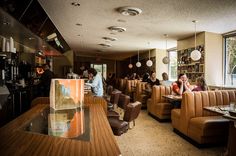 people sitting at tables in a restaurant with brown leather chairs and wooden counter tops,