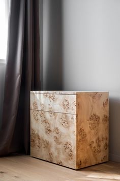 a wooden box sitting on top of a hard wood floor in front of a window