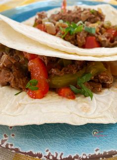 two tacos with meat and peppers on a plate