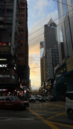 a city street filled with lots of traffic and tall buildings under a cloudy blue sky