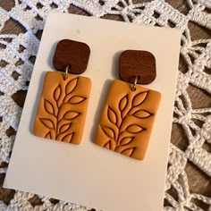 a pair of wooden earrings with leaves on them