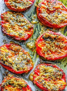 several tomatoes with seasoning on them sitting on a piece of parchment paper