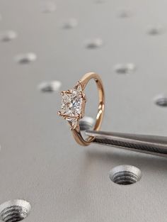 a close up of a diamond ring on top of a piece of metal with holes in the background