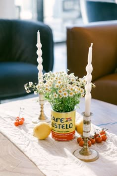 a table with candles, lemons and flowers on it in front of a couch