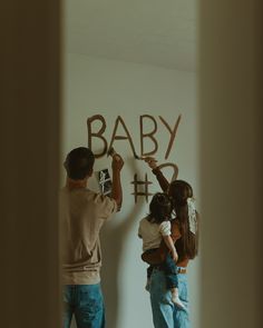 a man and woman are writing the word baby on a wall