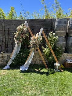 an outdoor ceremony setup with flowers and greenery on the back wall, next to wine barrels