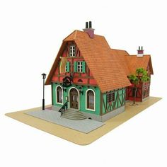 a paper model of a green and red house with a clock on the front porch